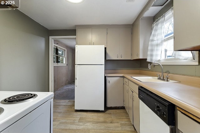 kitchen featuring white appliances, light countertops, a sink, and light wood finished floors