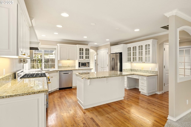 kitchen with light stone countertops, stainless steel appliances, a center island, and white cabinets