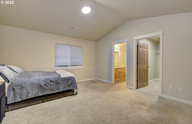 bedroom featuring ensuite bathroom, vaulted ceiling, and light colored carpet