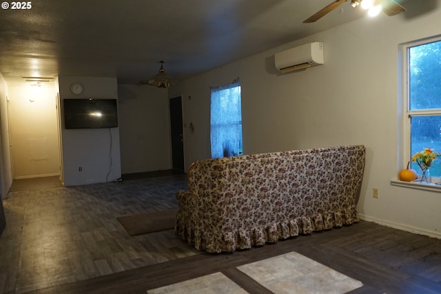 interior space featuring ceiling fan, a wall unit AC, wood finished floors, and baseboards