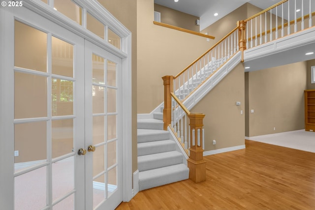 7917 NW Blue Pointe Ln, Portland, OR 97229 - staircase with wood finished floors, french doors, a towering ceiling, baseboards, and recessed lighting