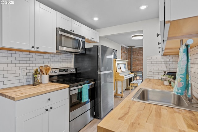 251 NE Village Squire Ave Unit 2, Gresham, OR 97030 - kitchen with appliances with stainless steel finishes, butcher block countertops, tasteful backsplash, white cabinetry, and recessed lighting
