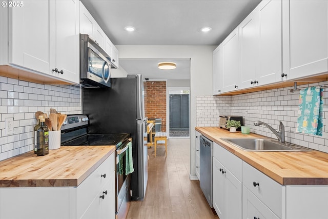 251 NE Village Squire Ave Unit 2, Gresham, OR 97030 - kitchen with butcher block countertops, stainless steel appliances, tasteful backsplash, light wood finished floors, and recessed lighting