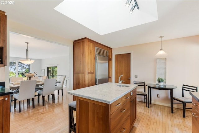31430 NE Canter Ln, Sherwood, OR 97140 - kitchen featuring stainless steel built in fridge, brown cabinetry, light wood finished floors, light stone countertops, and hanging light fixtures