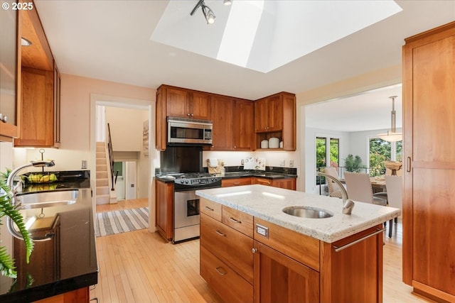 31430 NE Canter Ln, Sherwood, OR 97140 - kitchen featuring stainless steel appliances, light wood finished floors, an island with sink, light stone counters, and brown cabinets