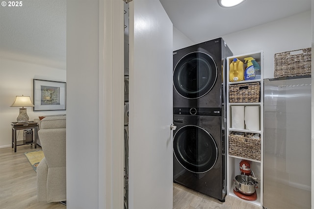 laundry room with stacked washer / dryer and light wood-type flooring