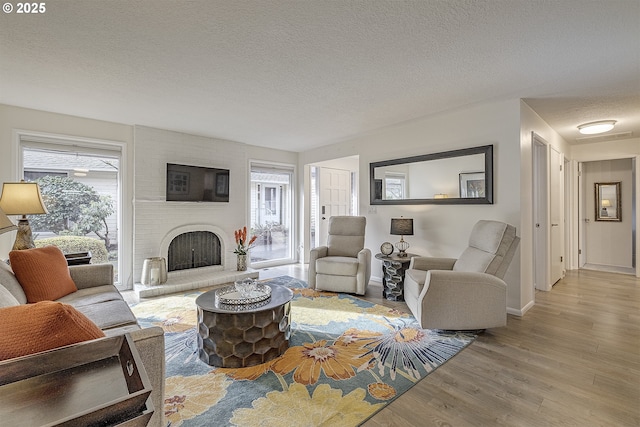 living room with a fireplace, light hardwood / wood-style flooring, and a textured ceiling