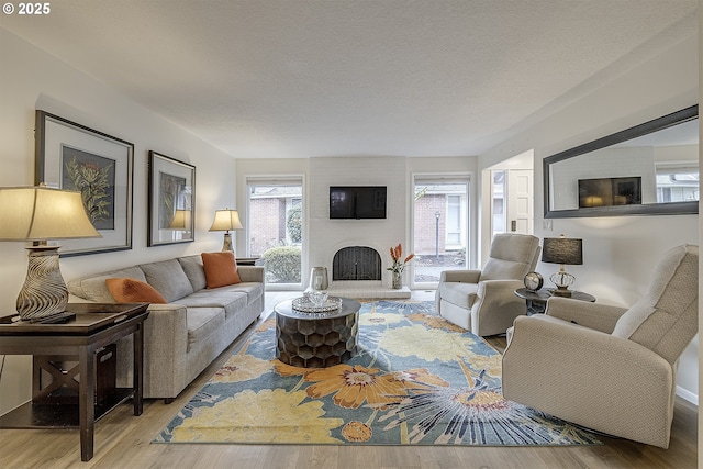 living room with a brick fireplace, hardwood / wood-style floors, and a textured ceiling