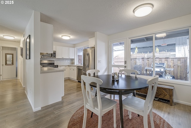 dining room featuring sink, a textured ceiling, and light wood-type flooring