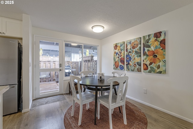 dining space featuring hardwood / wood-style floors and a textured ceiling