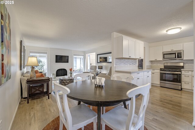 dining space featuring a large fireplace, light hardwood / wood-style flooring, and a textured ceiling