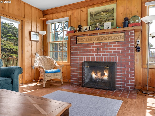living room with wood walls, hardwood / wood-style floors, a brick fireplace, and plenty of natural light