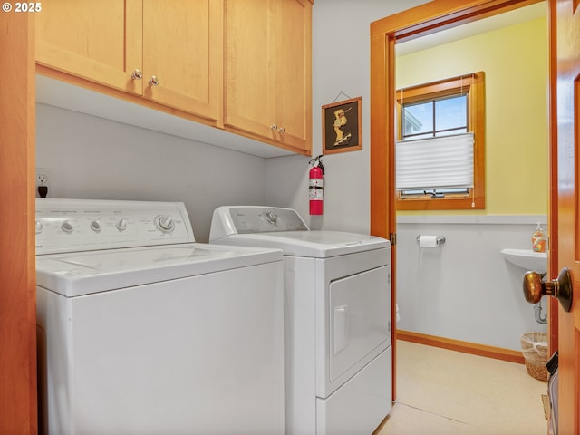 laundry area featuring separate washer and dryer, cabinet space, and wainscoting