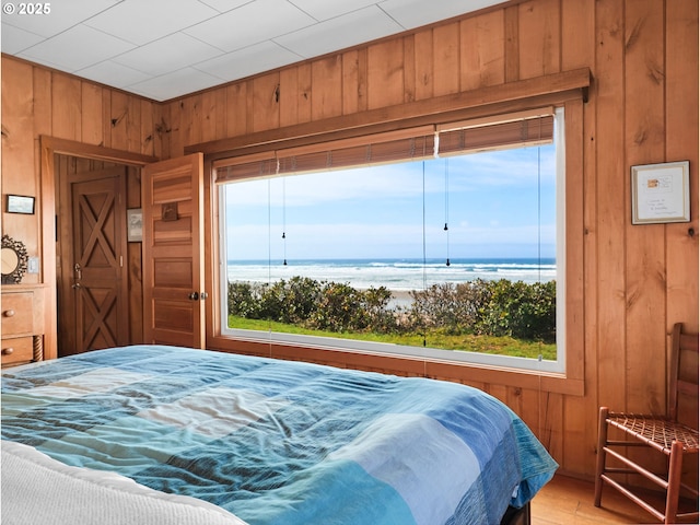 bedroom featuring wood walls, multiple windows, and a water view