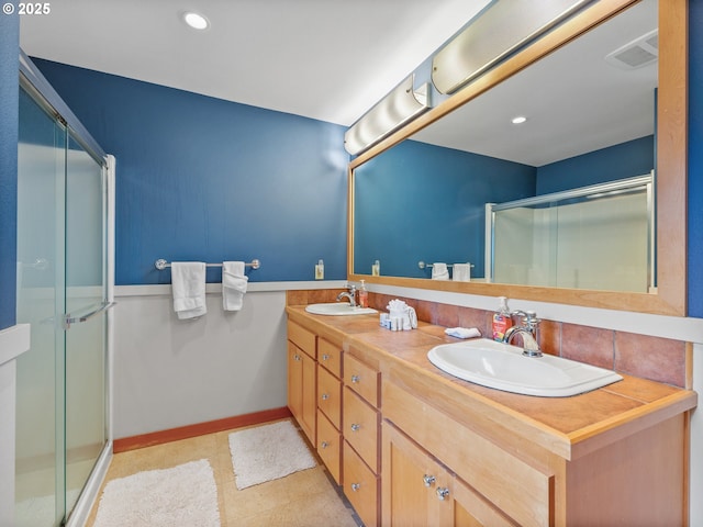 bathroom with a shower stall, double vanity, recessed lighting, and baseboards