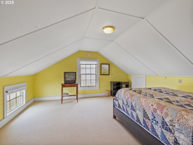 carpeted bedroom featuring wooden walls and vaulted ceiling