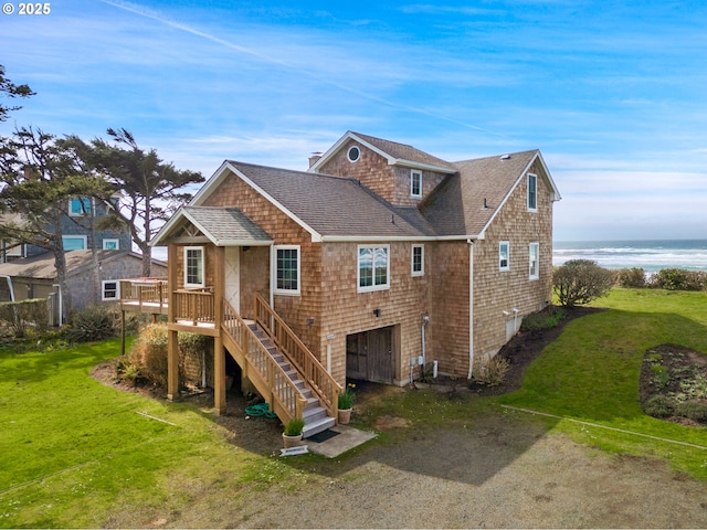 back of property with dirt driveway, a shingled roof, a lawn, and a garage