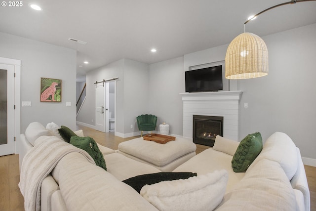 living area with recessed lighting, wood finished floors, visible vents, and a barn door