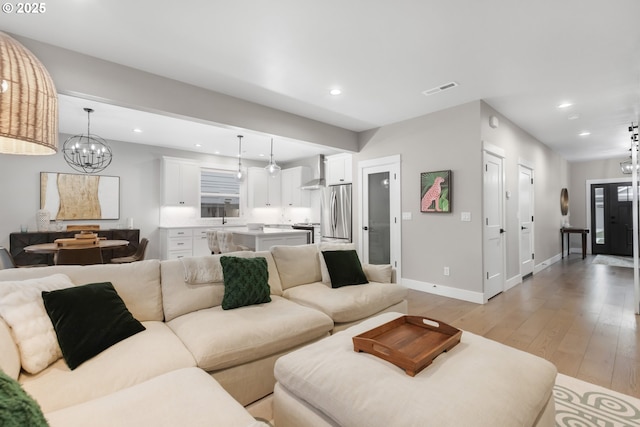 living room featuring recessed lighting, visible vents, a chandelier, light wood-type flooring, and baseboards