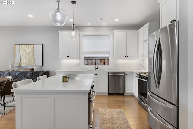 kitchen with a sink, white cabinets, light countertops, appliances with stainless steel finishes, and backsplash