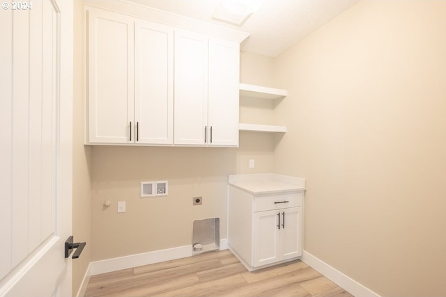 laundry area featuring electric dryer hookup, cabinets, gas dryer hookup, hookup for a washing machine, and light hardwood / wood-style flooring