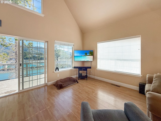 living room with light wood-type flooring and high vaulted ceiling