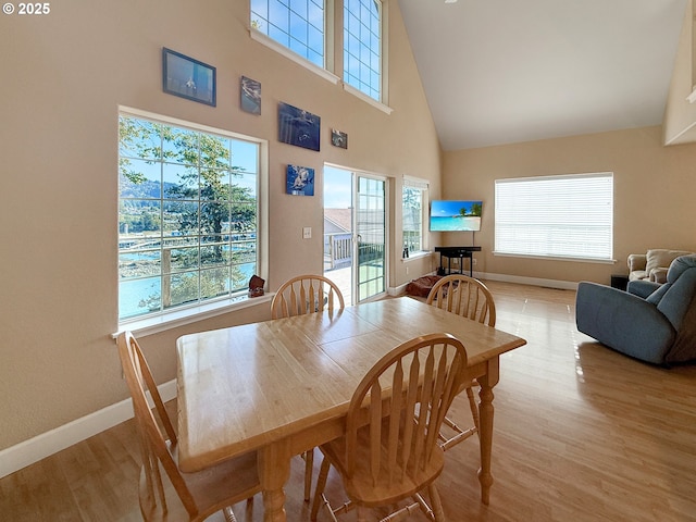 dining area featuring high vaulted ceiling, plenty of natural light, and light hardwood / wood-style floors