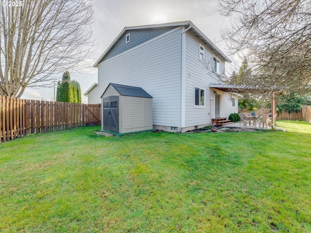 back of property featuring entry steps, a fenced backyard, an outbuilding, a storage unit, and a yard