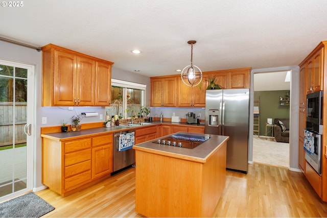 kitchen featuring appliances with stainless steel finishes, a kitchen island, light wood-type flooring, and a sink