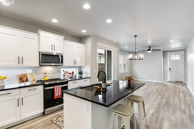 6429 SE Provence St, Hillsboro, OR 97123 - kitchen featuring appliances with stainless steel finishes, a sink, light wood-type flooring, an island with sink, and tasteful backsplash
