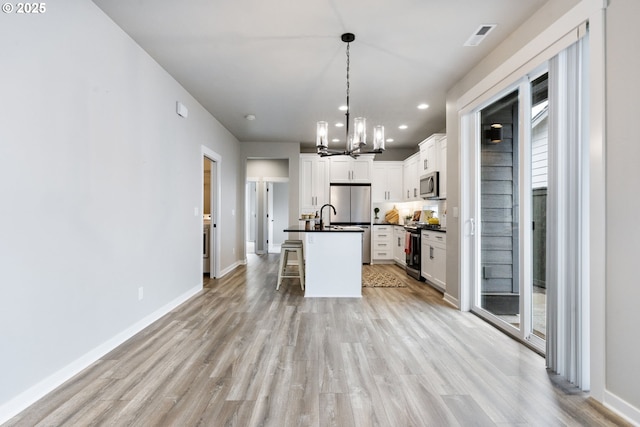 6429 SE Provence St, Hillsboro, OR 97123 - kitchen featuring appliances with stainless steel finishes, dark countertops, a chandelier, light wood-style flooring, and white cabinets