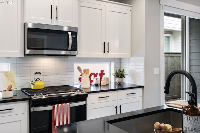 6429 SE Provence St, Hillsboro, OR 97123 - kitchen featuring stainless steel microwave, gas range, dark countertops, and white cabinetry