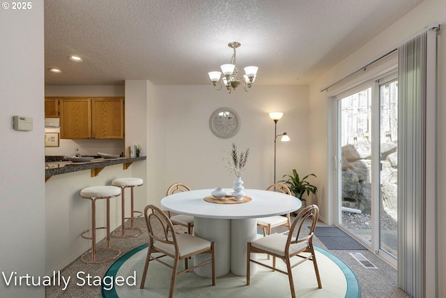 carpeted dining room with a textured ceiling, a chandelier, and recessed lighting