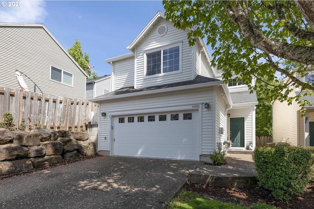 traditional-style house featuring an attached garage, asphalt driveway, and fence