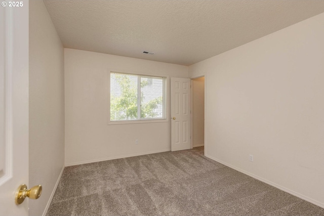 spare room with carpet flooring, a textured ceiling, and baseboards