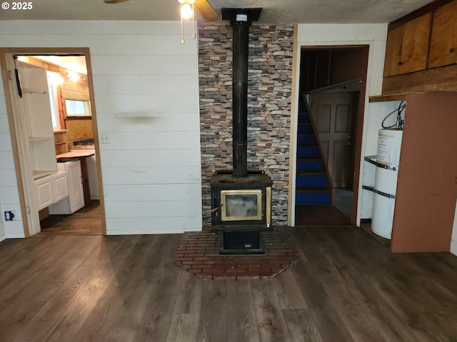 82284 Hillview Dr, Creswell, OR 97426 - unfurnished living room with wooden walls, a wood stove, dark wood-style floors, secured water heater, and ceiling fan