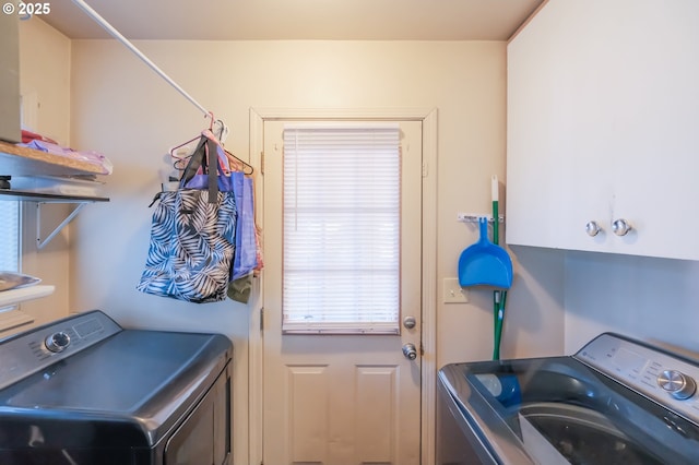 clothes washing area with separate washer and dryer and cabinets