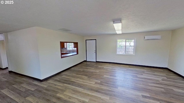 132 NE Rifle Range St, Roseburg, OR 97470 - spare room with an AC wall unit, wood finished floors, healthy amount of natural light, baseboards, and a textured ceiling