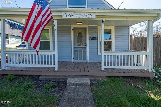 property entrance with a porch and fence