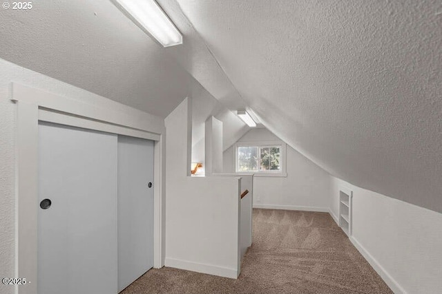 bonus room with a textured ceiling, carpet flooring, vaulted ceiling, and baseboards