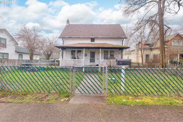 view of front facade featuring a fenced front yard, a chimney, covered porch, a gate, and a front lawn