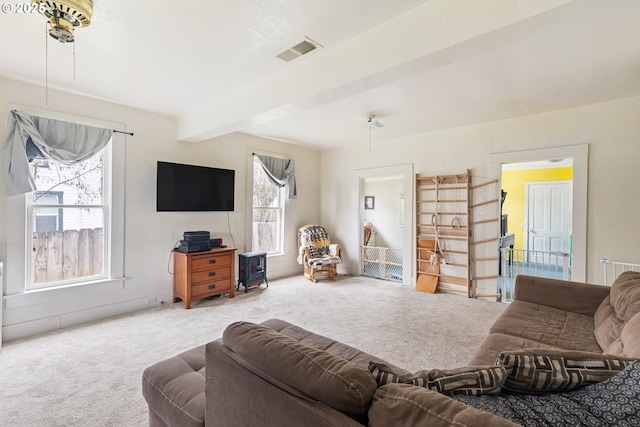 living area with visible vents, beamed ceiling, and carpet flooring