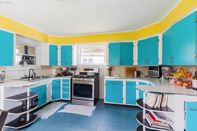 kitchen with light countertops, stainless steel gas stove, a sink, and dark floors