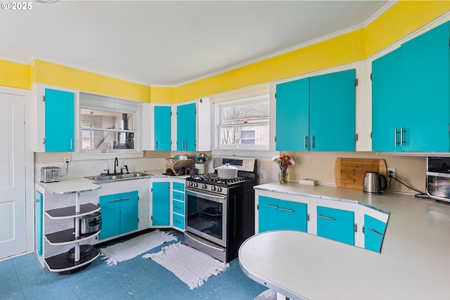 kitchen with stainless steel gas stove, ornamental molding, light countertops, blue cabinetry, and a sink