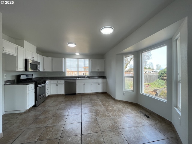 5145 Trevon St, Eugene, OR 97402 - kitchen with appliances with stainless steel finishes, dark countertops, white cabinetry, and tile patterned flooring