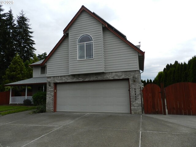 31811 NW Belgium Ct, North Plains, OR 97133 - view of home's exterior with a gate, brick siding, driveway, and a garage