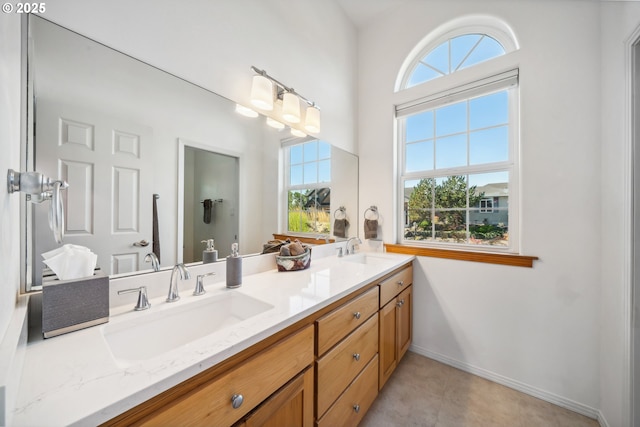 bathroom featuring baseboards, double vanity, a sink, and tile patterned floors