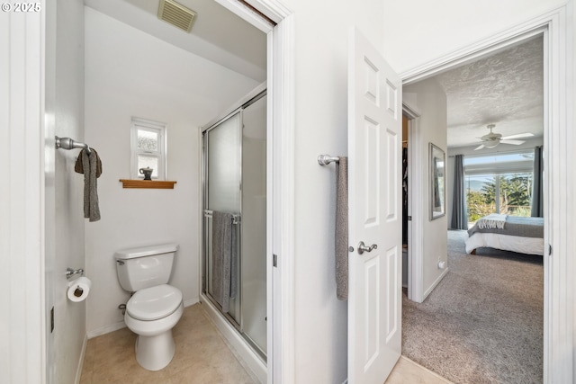ensuite bathroom with toilet, a stall shower, tile patterned floors, and visible vents