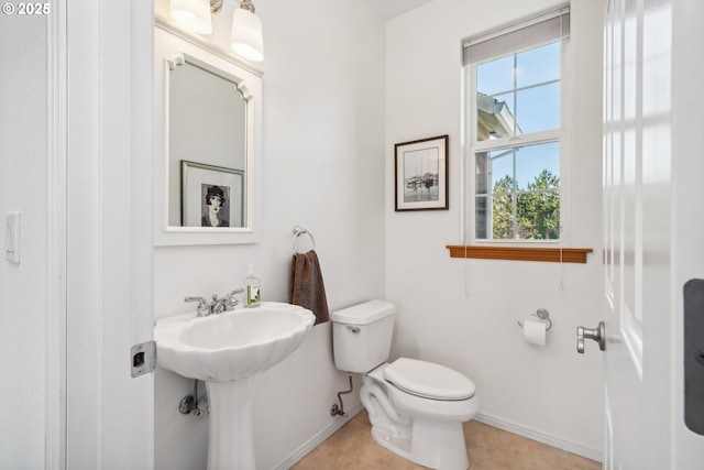 bathroom featuring baseboards, toilet, tile patterned floors, and a sink