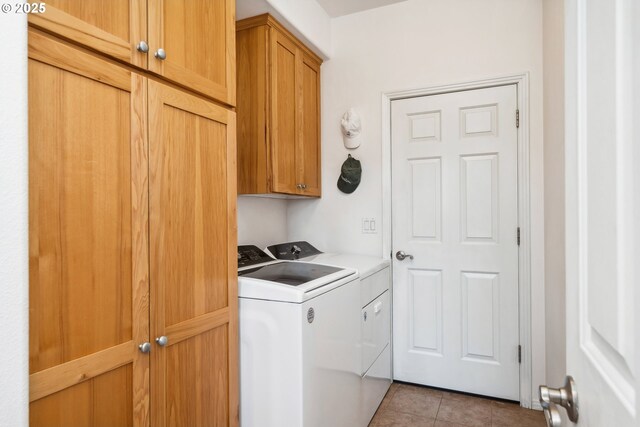 clothes washing area with cabinet space, tile patterned floors, and washer and clothes dryer